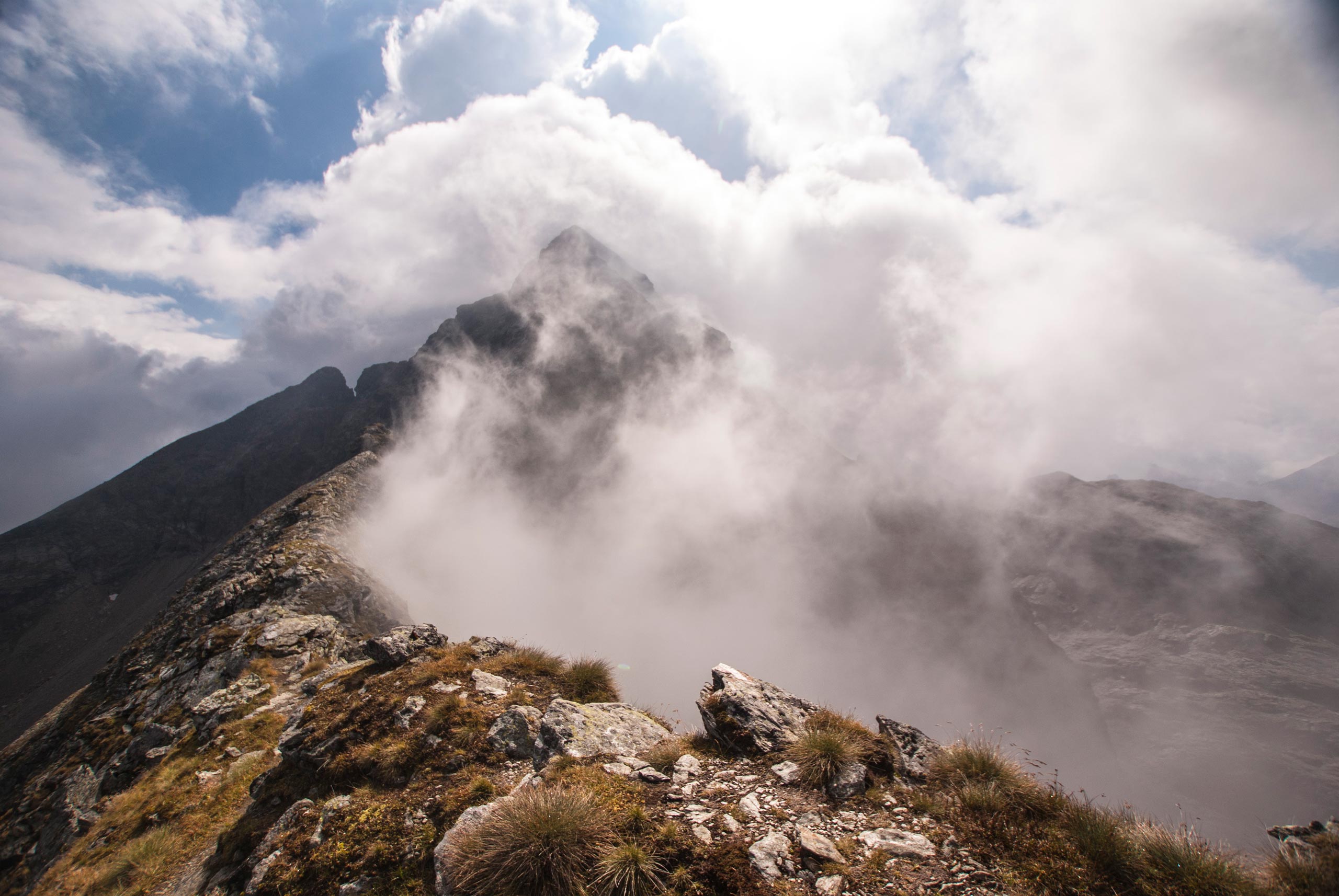 blick von der kleinen wildstelle über den nordgrat zur hochwildstelle in rohrmoos. wolken ziehen an deren flanke empor.